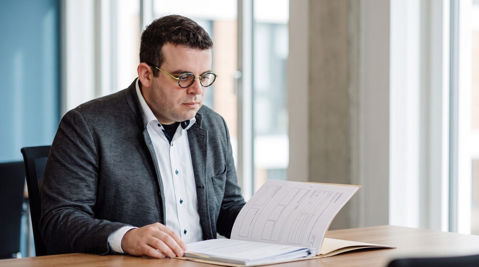 Felix Wilhelm prüft eine Vertragsakte am Schreibtisch