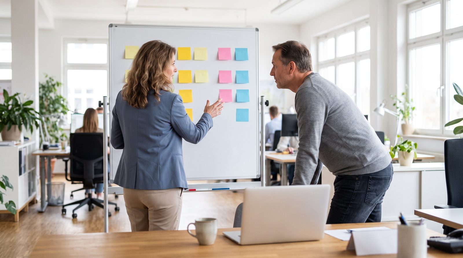 Büroleiterin vergleicht am Whiteboard verschiedene Optionen mit ihrem Team in einem mittelständischen Unternehmen