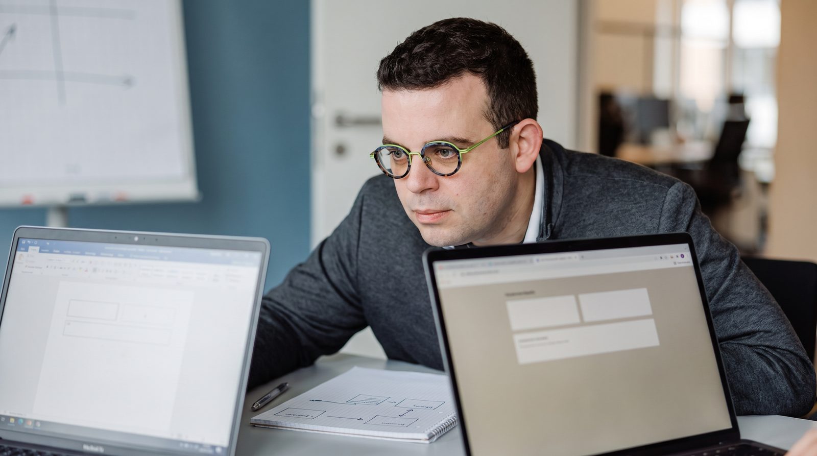 Felix Wilhelm vergleicht zwei Werkzeuge an nebeneinanderstehenden Laptops